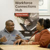 Ulicia Lawrence Oladeinde talking with a community partner with Workforce Connections sign behind them
