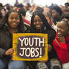Three female youth holding a sign that says "Youth Jobs"